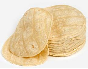 A stack of tortilla pancakes, two are leaning against the left hand side, as if they slipped off.